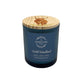 A dark blue glass jar candle with a light wood lid featuring a Highland cow, labelled 'Wild Woodland' by The Humble Hare. The candle scent is woody, earthy and smoky with oud and patchouli.