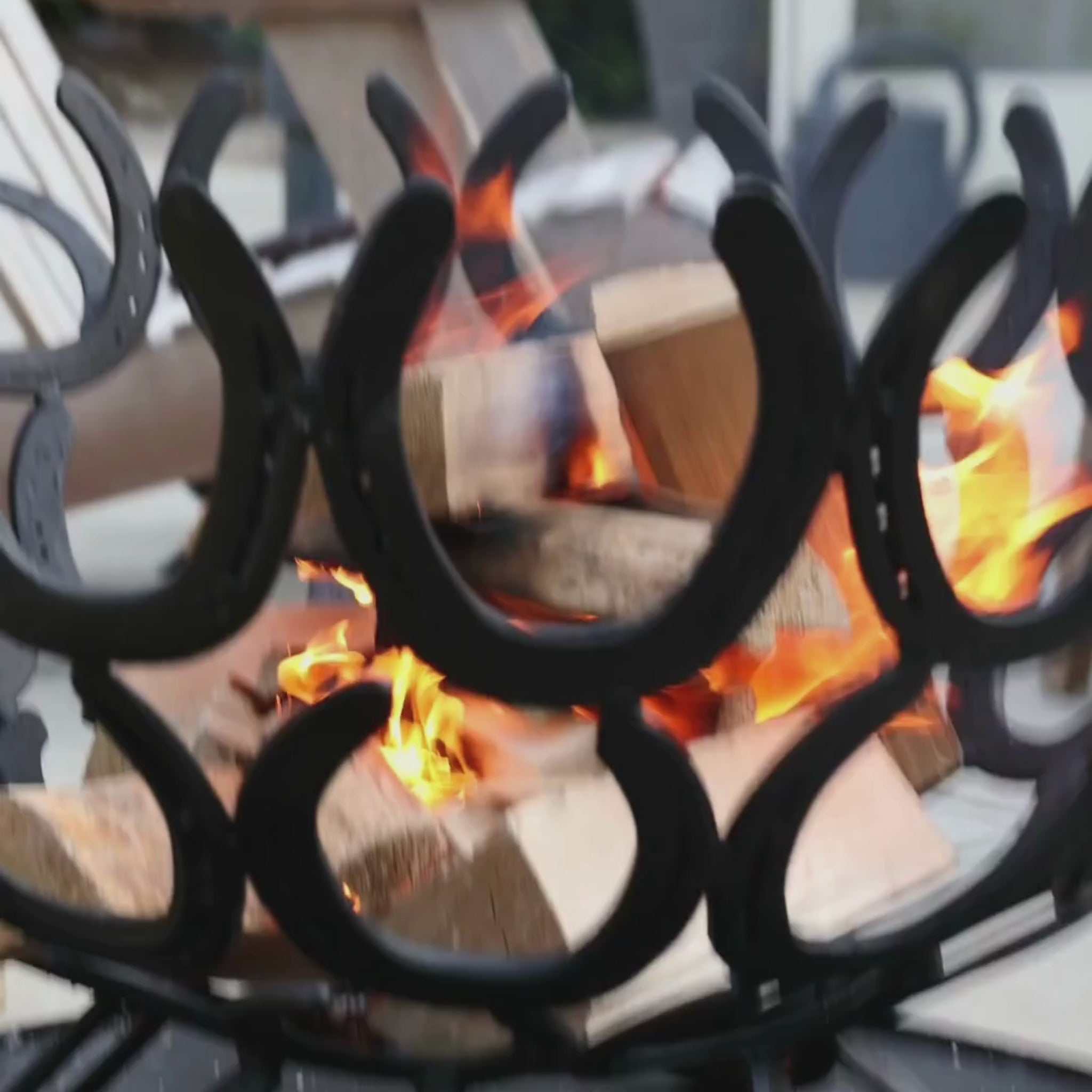 Slow motion footage of firewood being lit in a handmade horseshoe fire pit in a country garden.