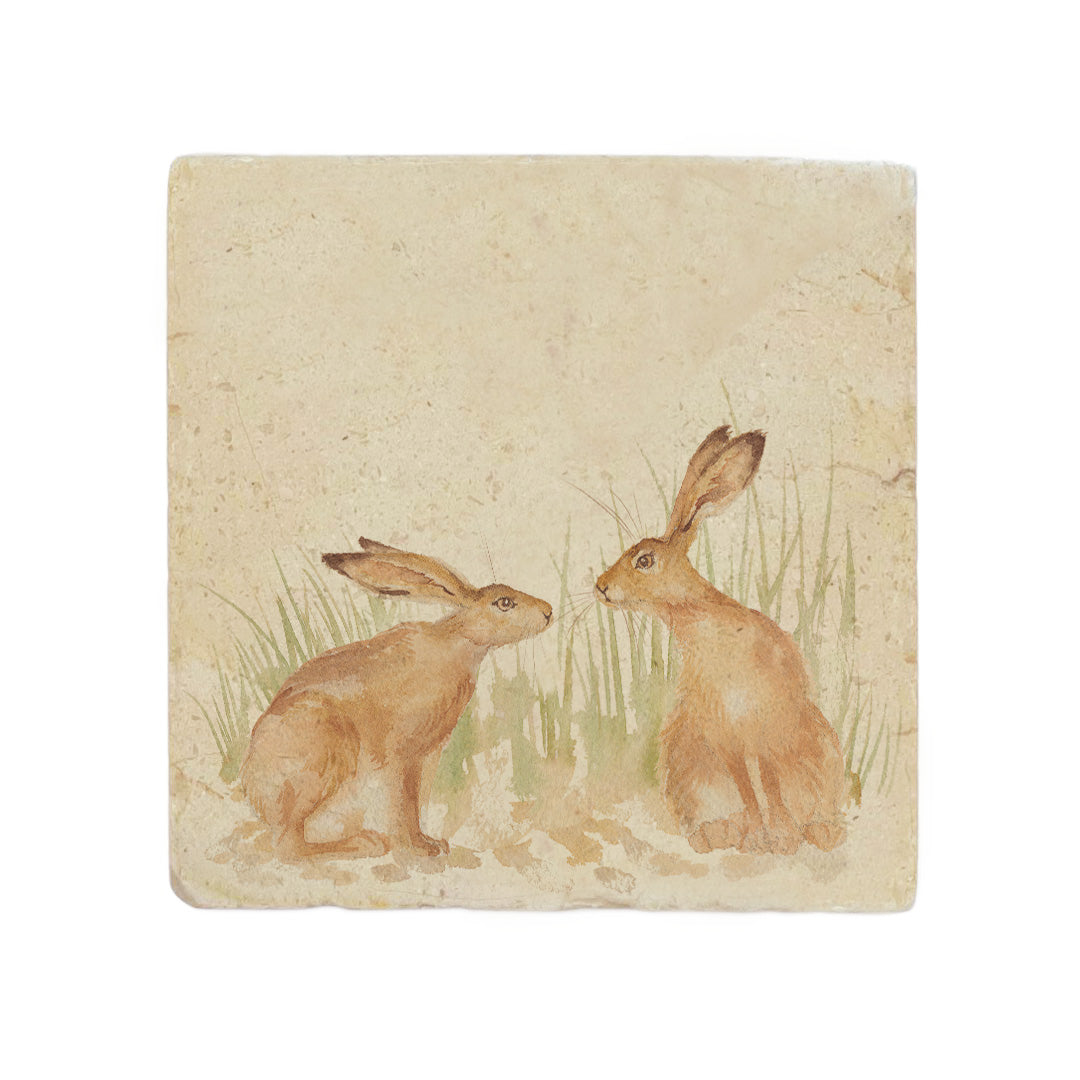 A handmade cream marble splashback tile featuring a watercolour countryside animal design of two hares in grass facing each other about to touch noses.